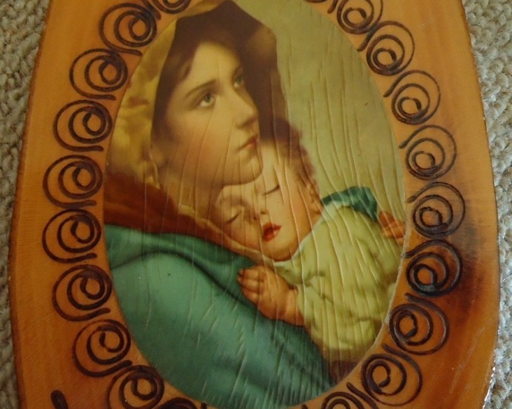 Bronskleurig kruisbeeld en religieuze afbeelding op hout.